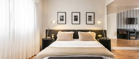 A modern hotel room with a large bed, two bedside tables, a flat-screen TV, and three framed pictures on the wall.