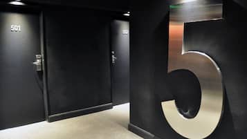 Corredor com portas numeradas 501 e 502, e um grande número 5 de metal na parede.