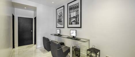 A modern reception area with a glass desk, two monitors, and framed pictures on the wall.