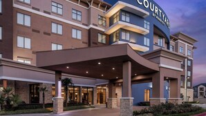 Ein Hotel der Courtyard by Marriott mit modernem Design, das mehrere Stockwerke, große Fenster und einen gut beleuchteten Eingang zeigt.