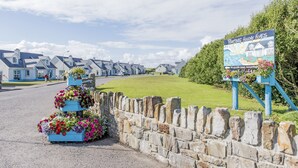A row of holiday homes with a stone wall and flower boxes in front. - Portbeg Holiday Homes at Donegal Bay (Bundoran)