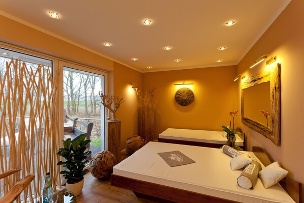 A modern hotel room with a large bed, a sitting area, and a view of the outdoors.