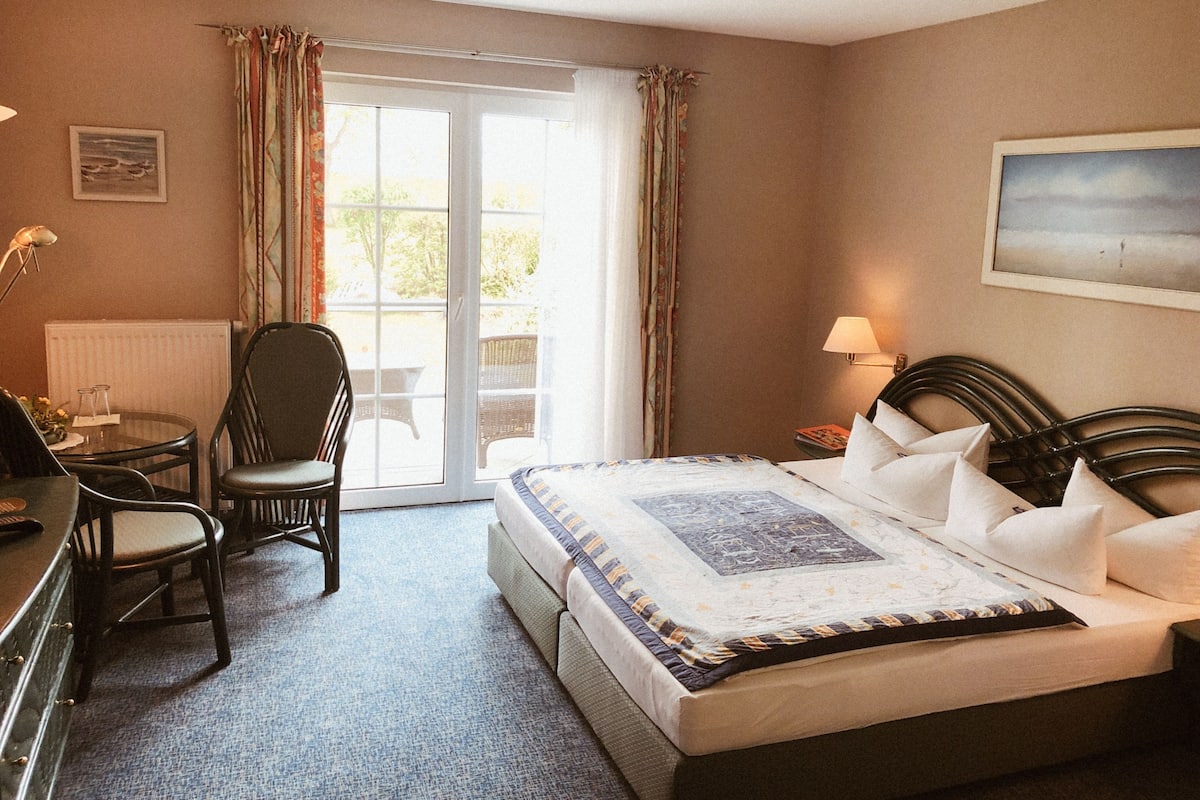 A hotel room with a bed, a desk, a chair, and a window with curtains.