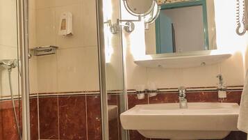 A bathroom with a glass-enclosed shower, a sink with a mirror above it, and a towel rack.