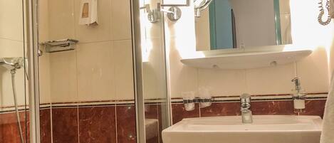 A bathroom with a glass-enclosed shower, a sink with a mirror above it, and a towel rack.
