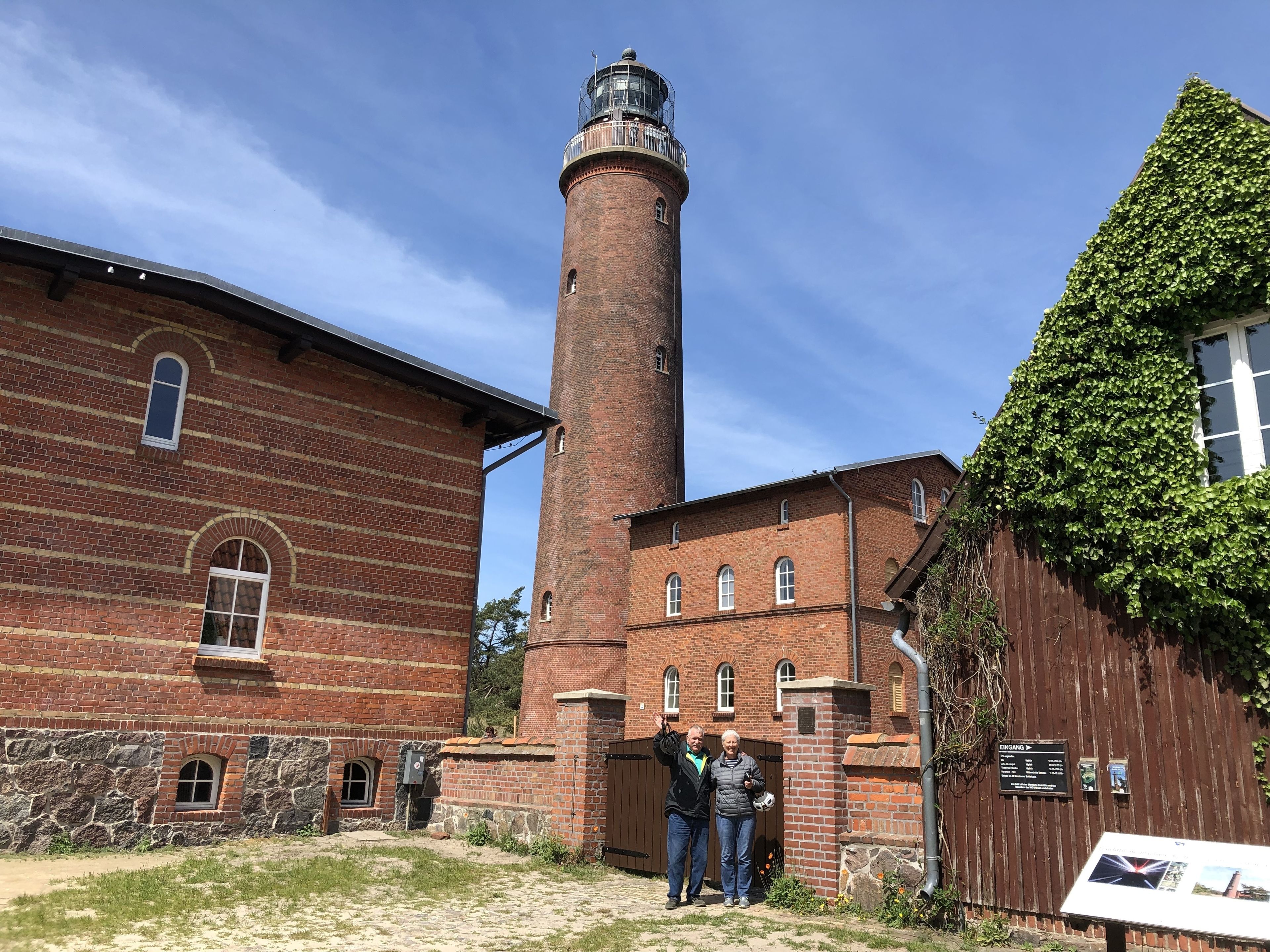 A brick building with a tall tower, a stone wall, and a wooden fence.