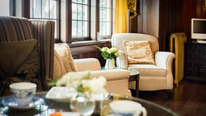 Una habitación acogedora con un sofá, un sillón y una mesa con tazas de té y un florero.
