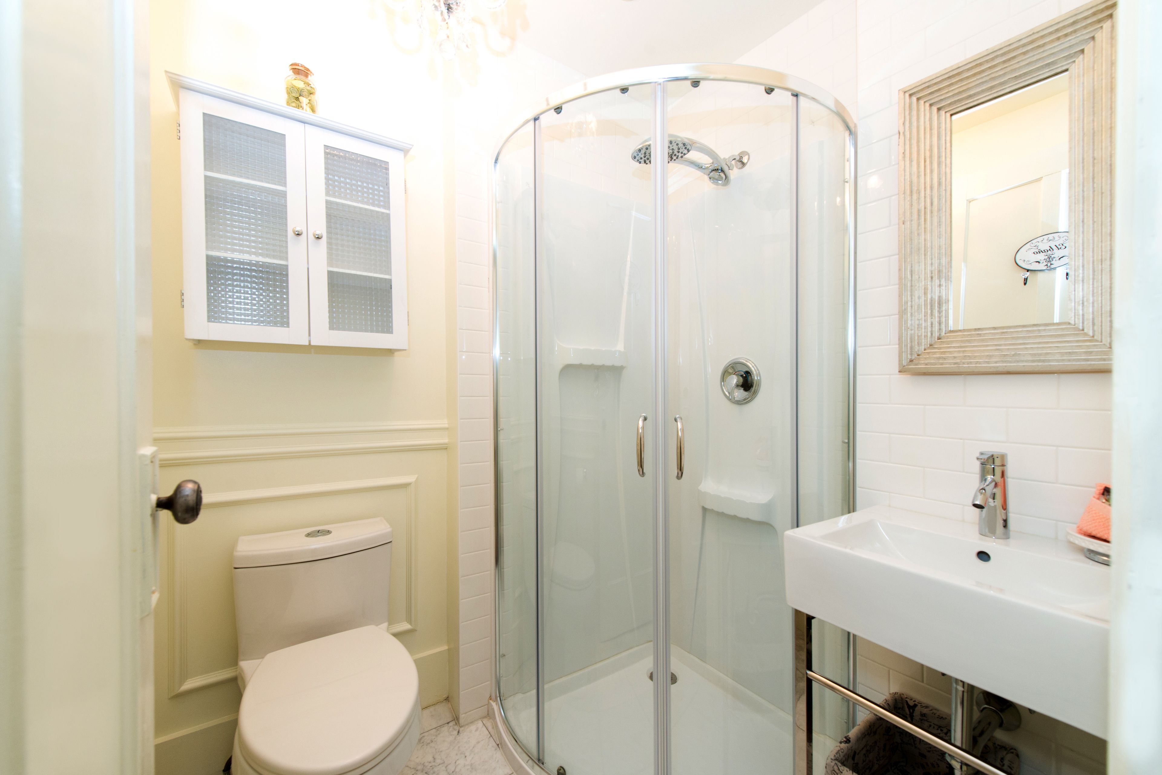 Une salle de bain comprenant des toilettes, une douche à parois de verre et un lavabo avec un miroir au-dessus.