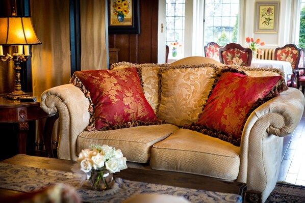 A traditional sofa with ornate cushions, a patterned rug, and a vase of flowers on a table.