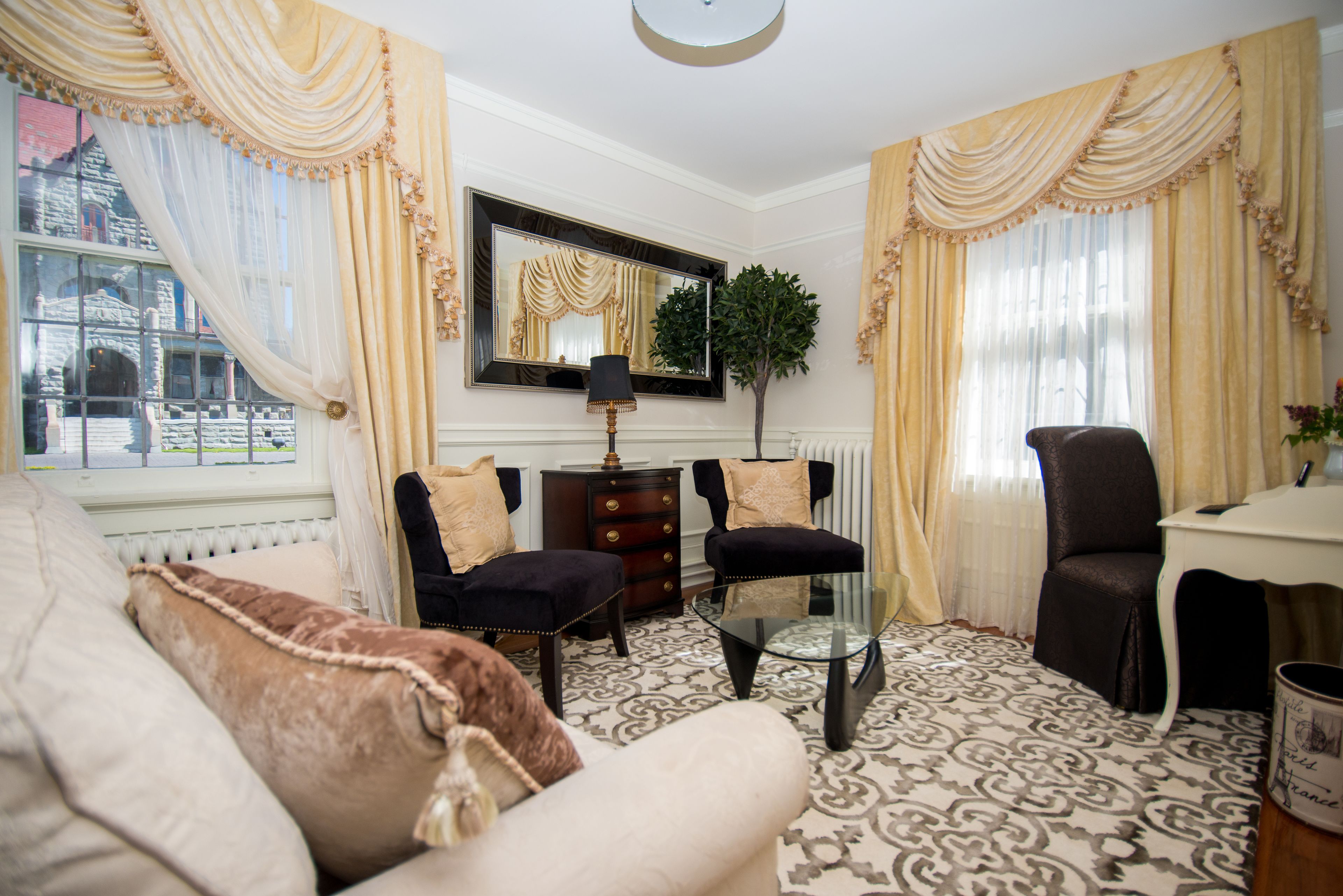 A traditional living room with a sofa, armchairs, a glass coffee table, and a side table.