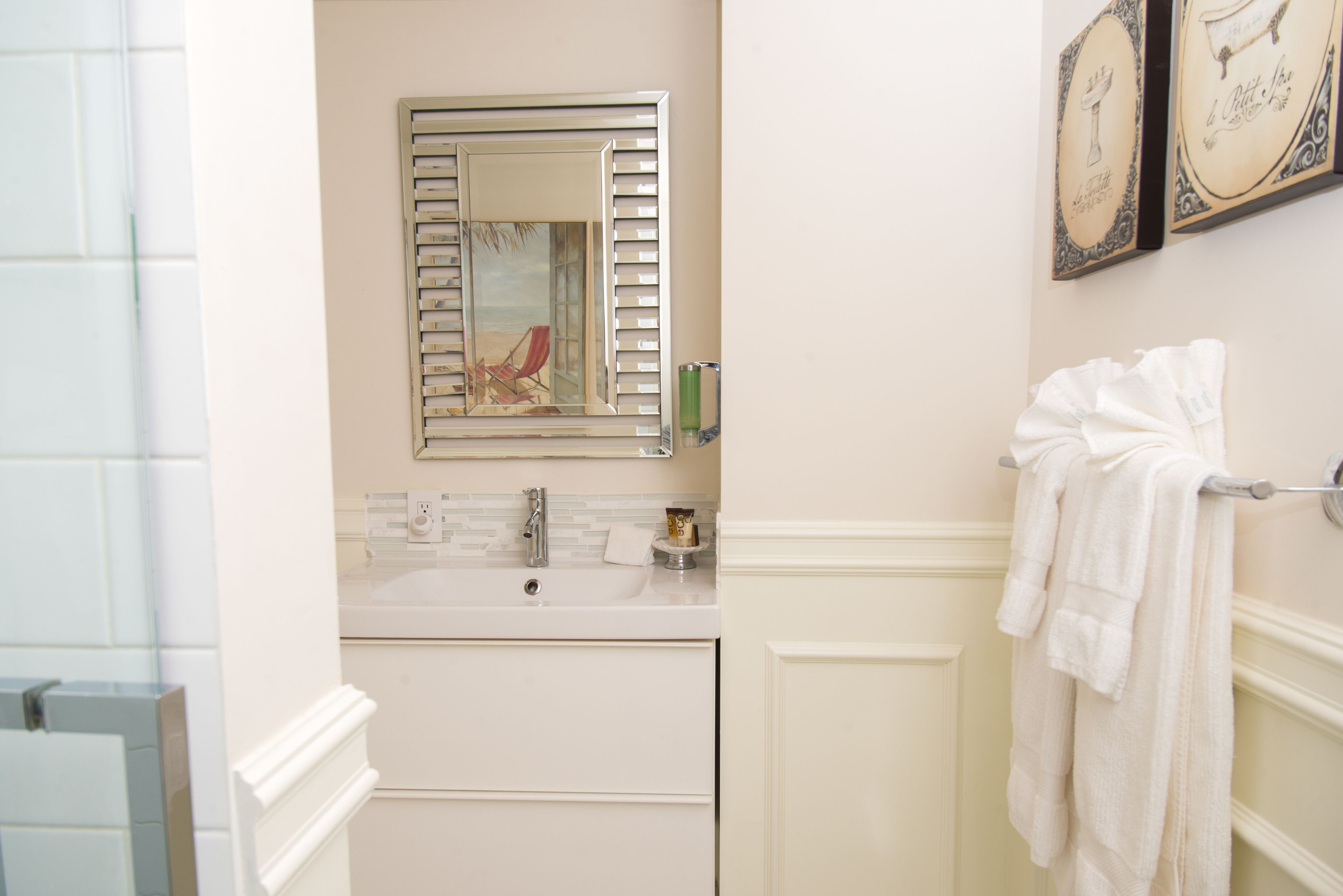 A bathroom with a white sink, a mirror with a decorative frame, and a towel rack with towels.