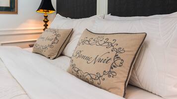 Una cama bien hecha con dos almohadones decorativos y una lámpara de noche.