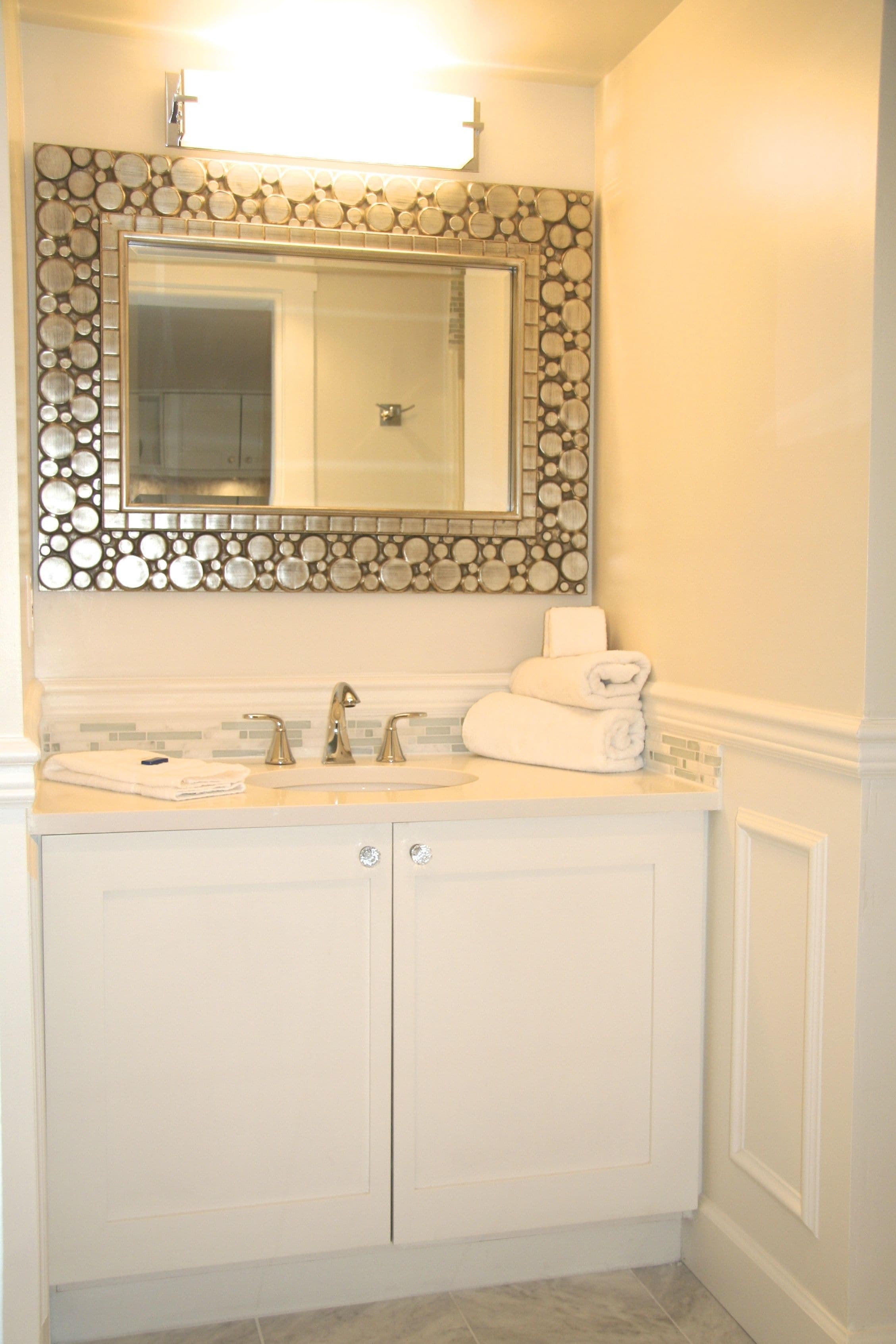 A bathroom with a large mirror, two sinks, and a decorative wall above the mirror.