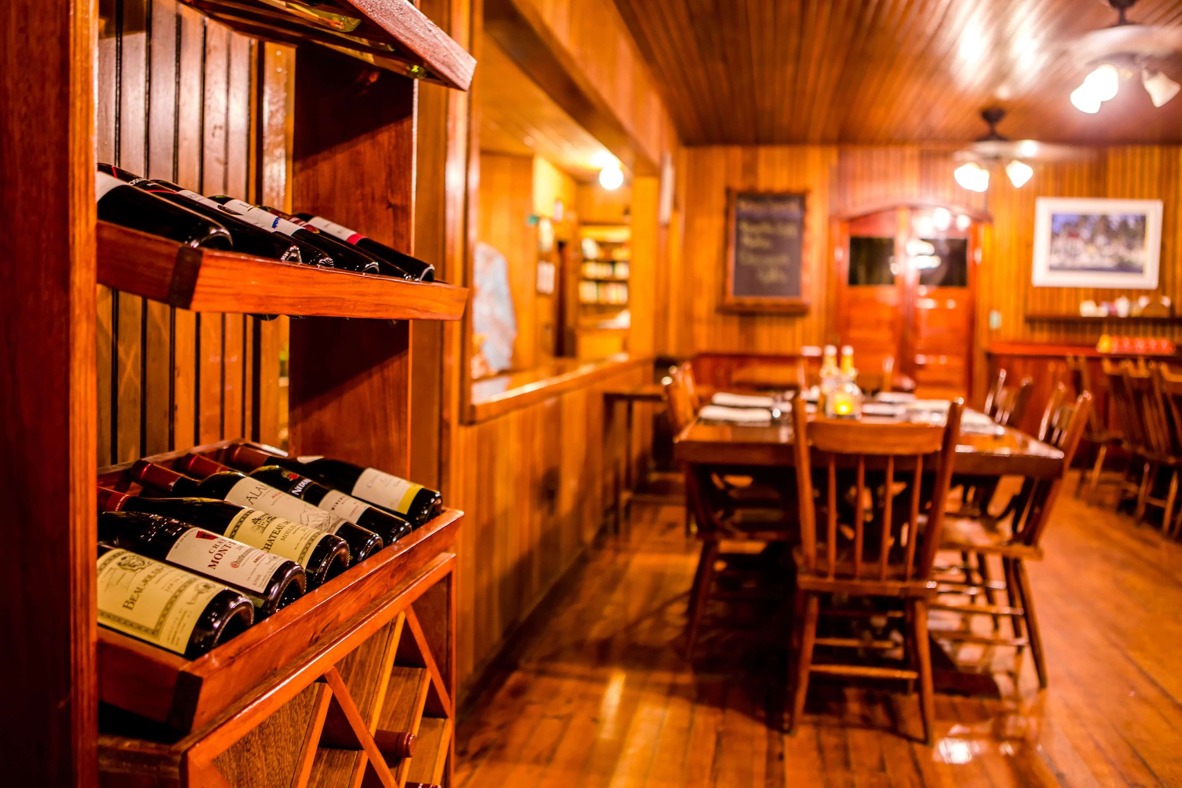 A wooden interior with a wine rack and tables.