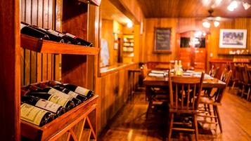 A wooden interior with a wine rack and tables.