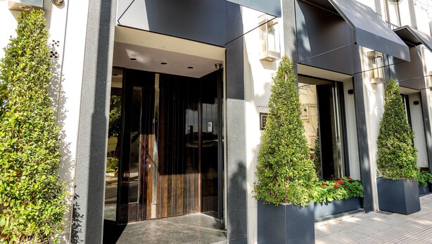 A modern building entrance with a dark facade, large glass doors, and potted plants. - Esplendor by Wyndham Buenos Aires Plaza Francia (Buenos Aires)