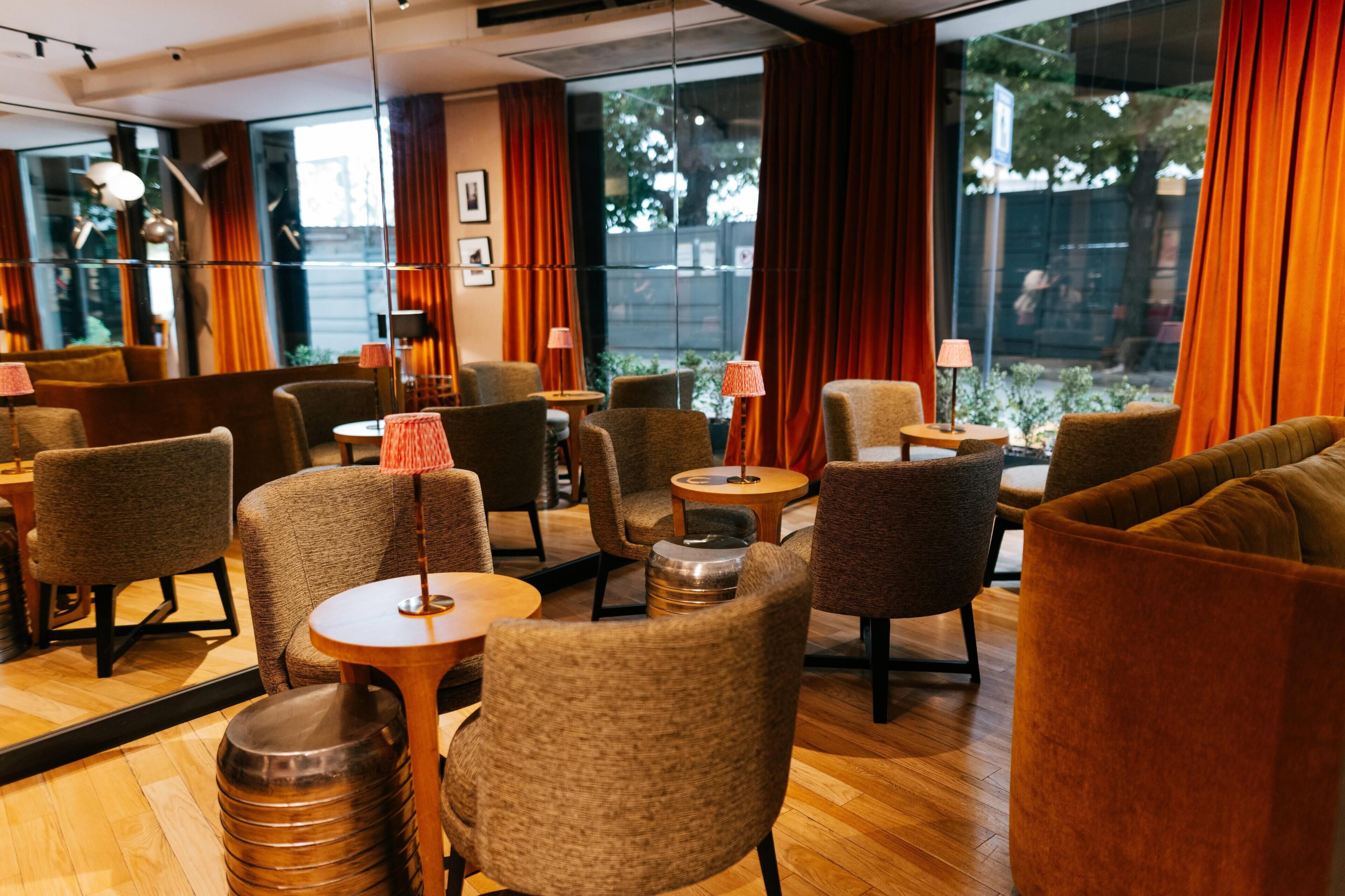 A modern interior with multiple seating areas, including sofas and chairs, arranged around tables and a bar area.