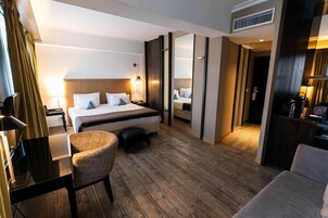 Una habitación de hotel moderna con una cama grande, un escritorio, una silla y un espejo.