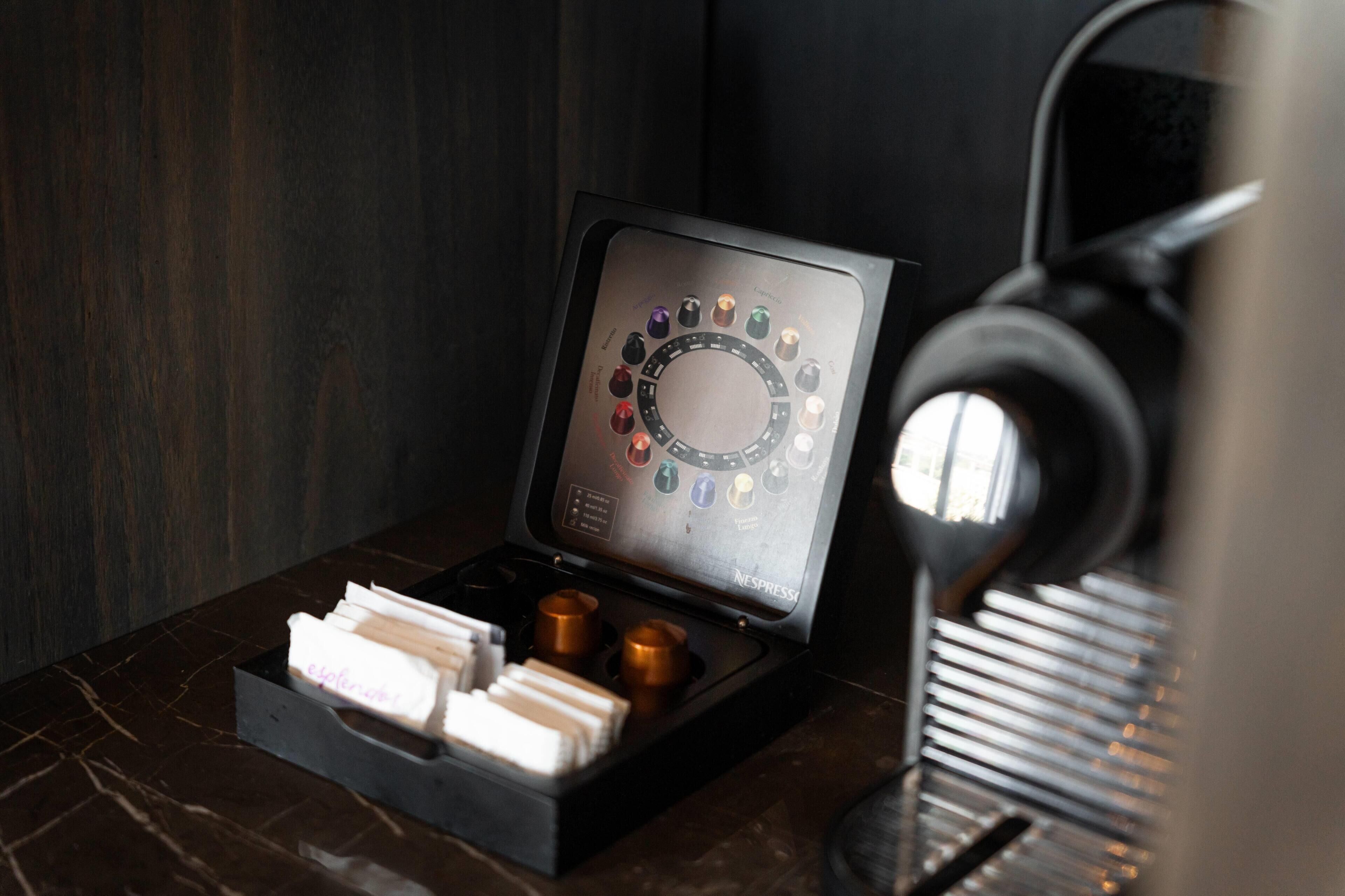 A coffee machine with a digital interface and a tray with coffee pods.