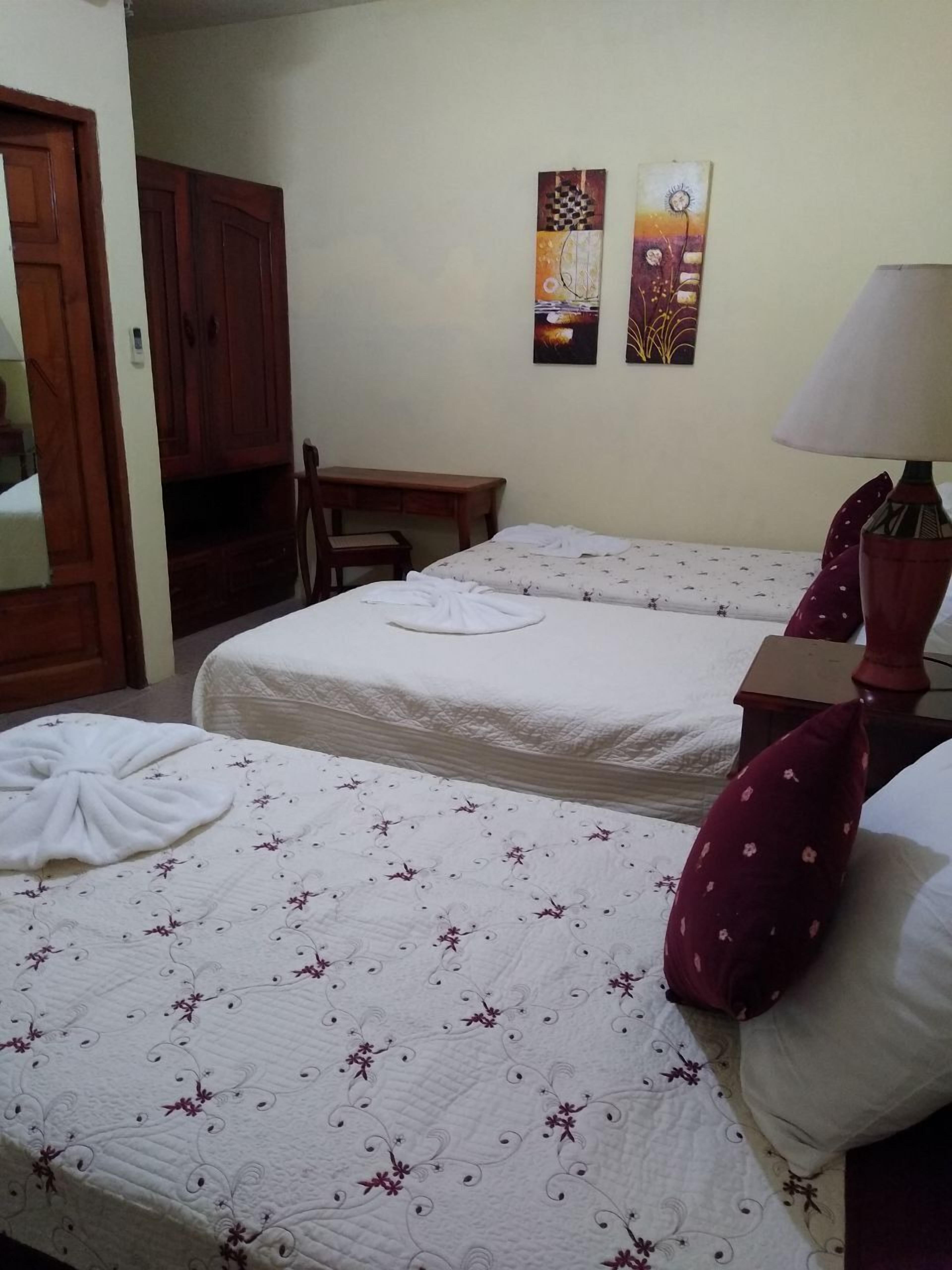 Una habitación de hotel con dos camas, un escritorio, una silla y una lámpara.