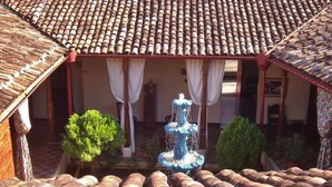 Ein Innenhof mit Brunnen, einem Ziegeldach und Kübelpflanzen.