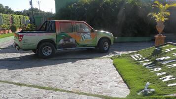 Un vehículo verde y naranja con el rótulo 'Maison' estacionado en un camino adoquinado.