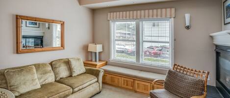A living room with a sofa, a chair, a window with blinds, a lamp, and a fireplace.