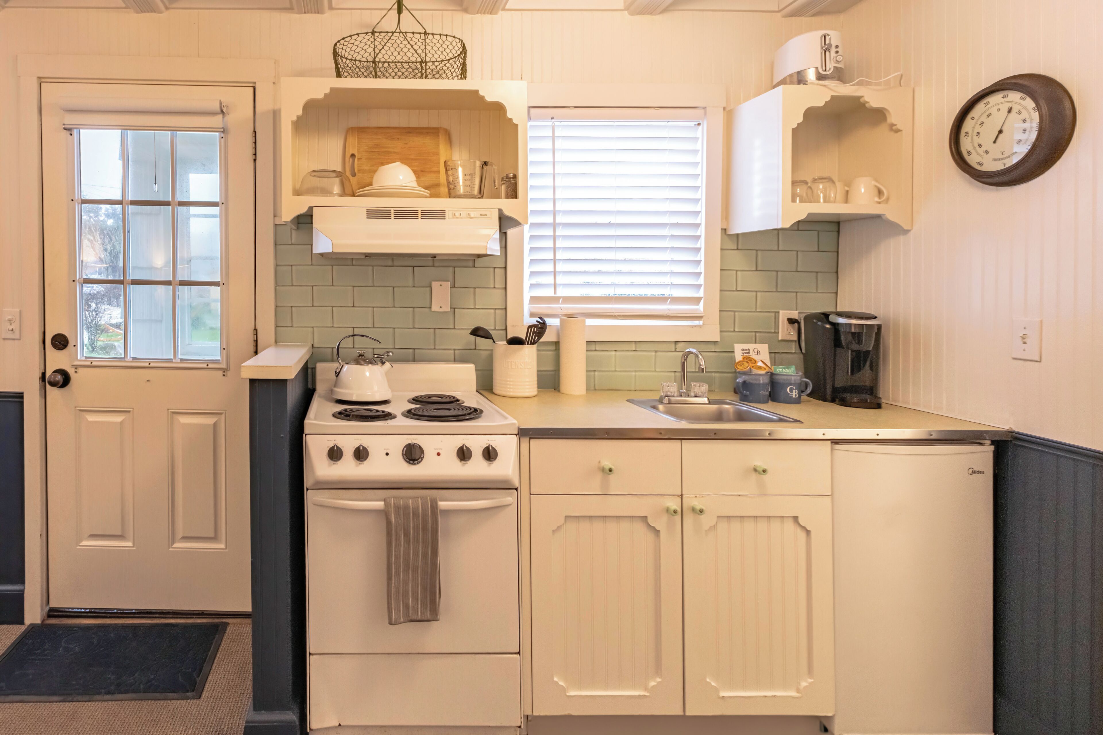 A kitchen with a stove, sink, and cabinets.