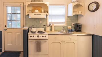 A kitchen with a stove, sink, and cabinets.