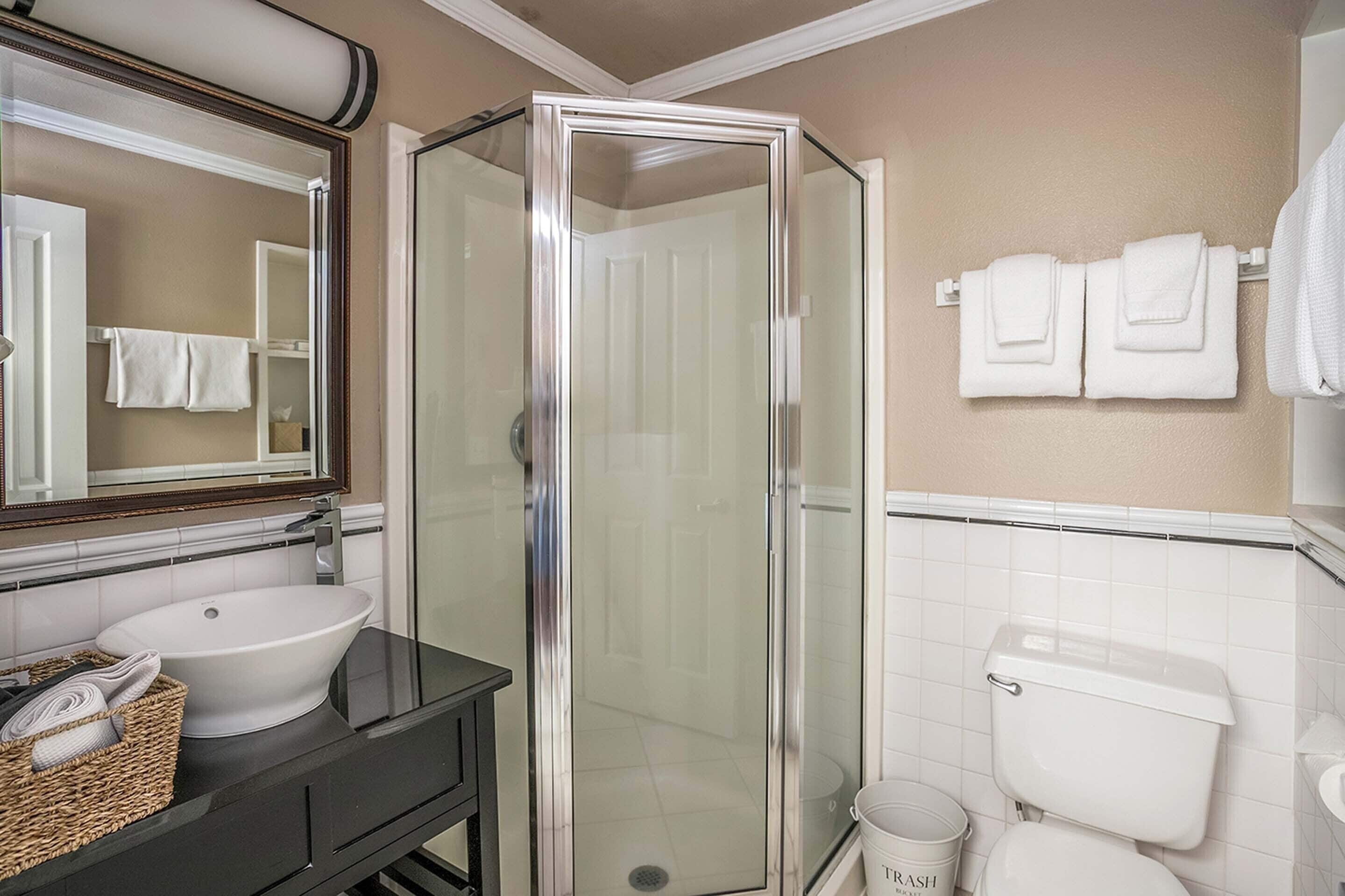 A bathroom with a glass-enclosed shower, a sink, and a toilet.