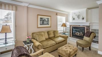 Una sala de estar con un sofá color crema, sillones y una chimenea.