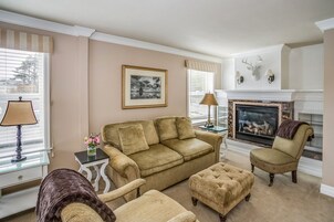 Una sala de estar con un sofá color crema, sillones y una chimenea.