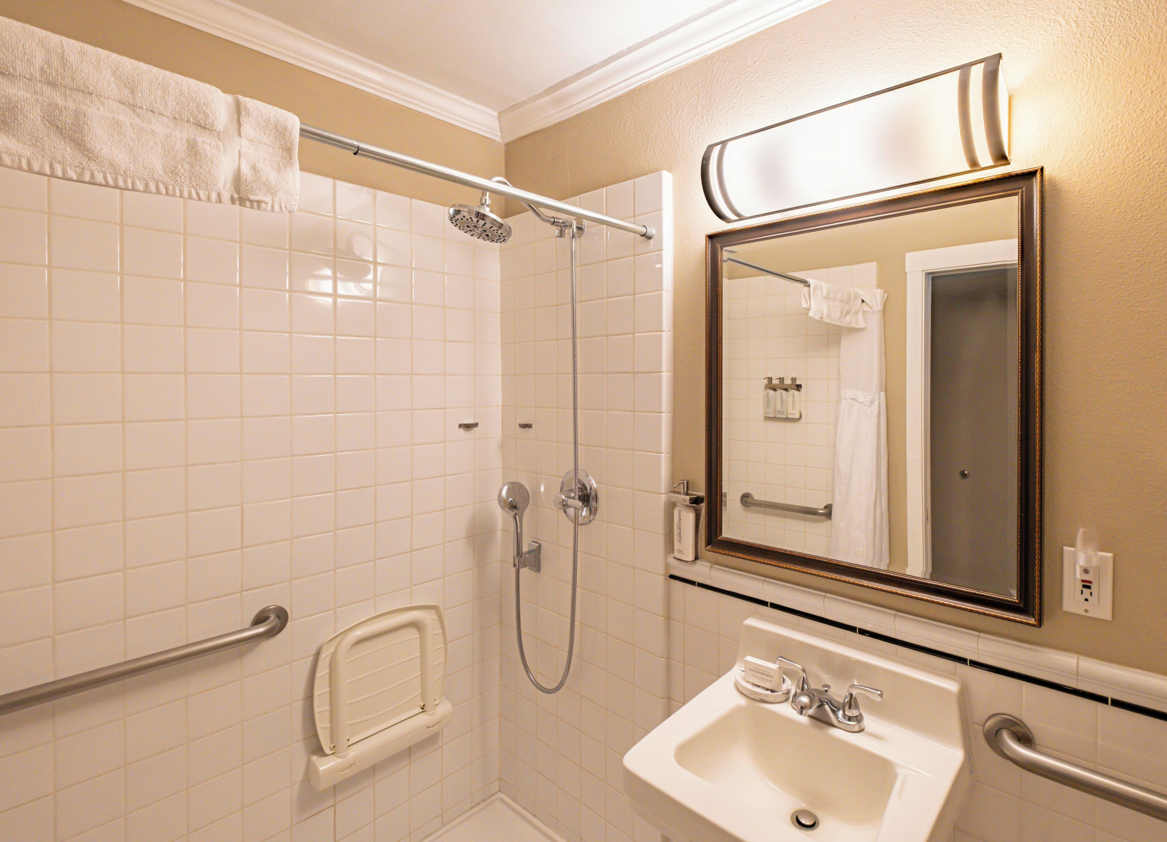 A bathroom with a walk-in shower, a sink, and a mirror.