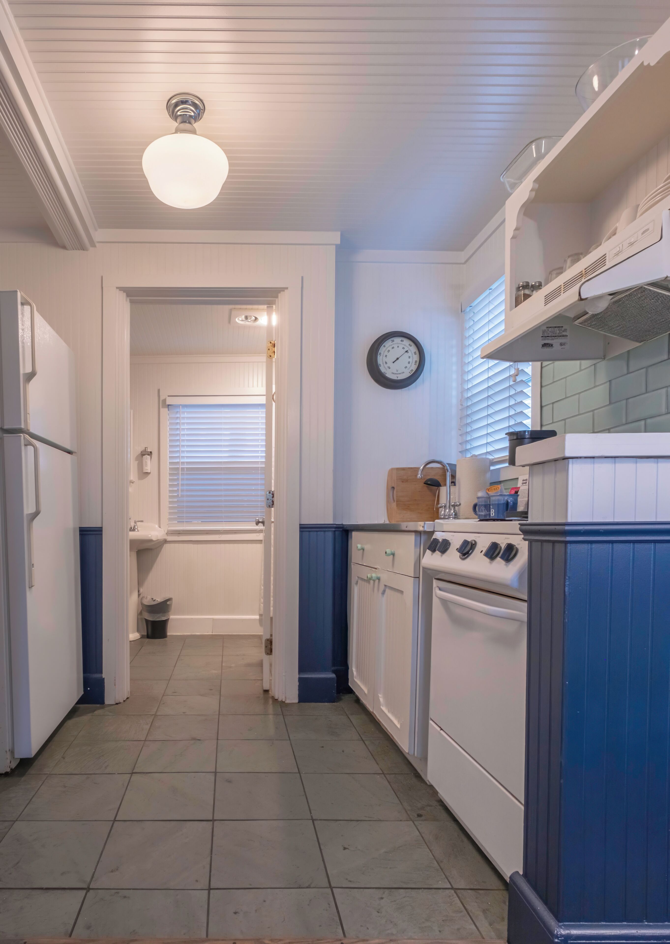 A kitchen with a stove, oven, and a clock on the wall.