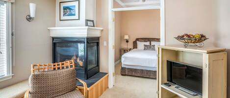 A cozy room with a fireplace, a television, a bed, and a dining area.