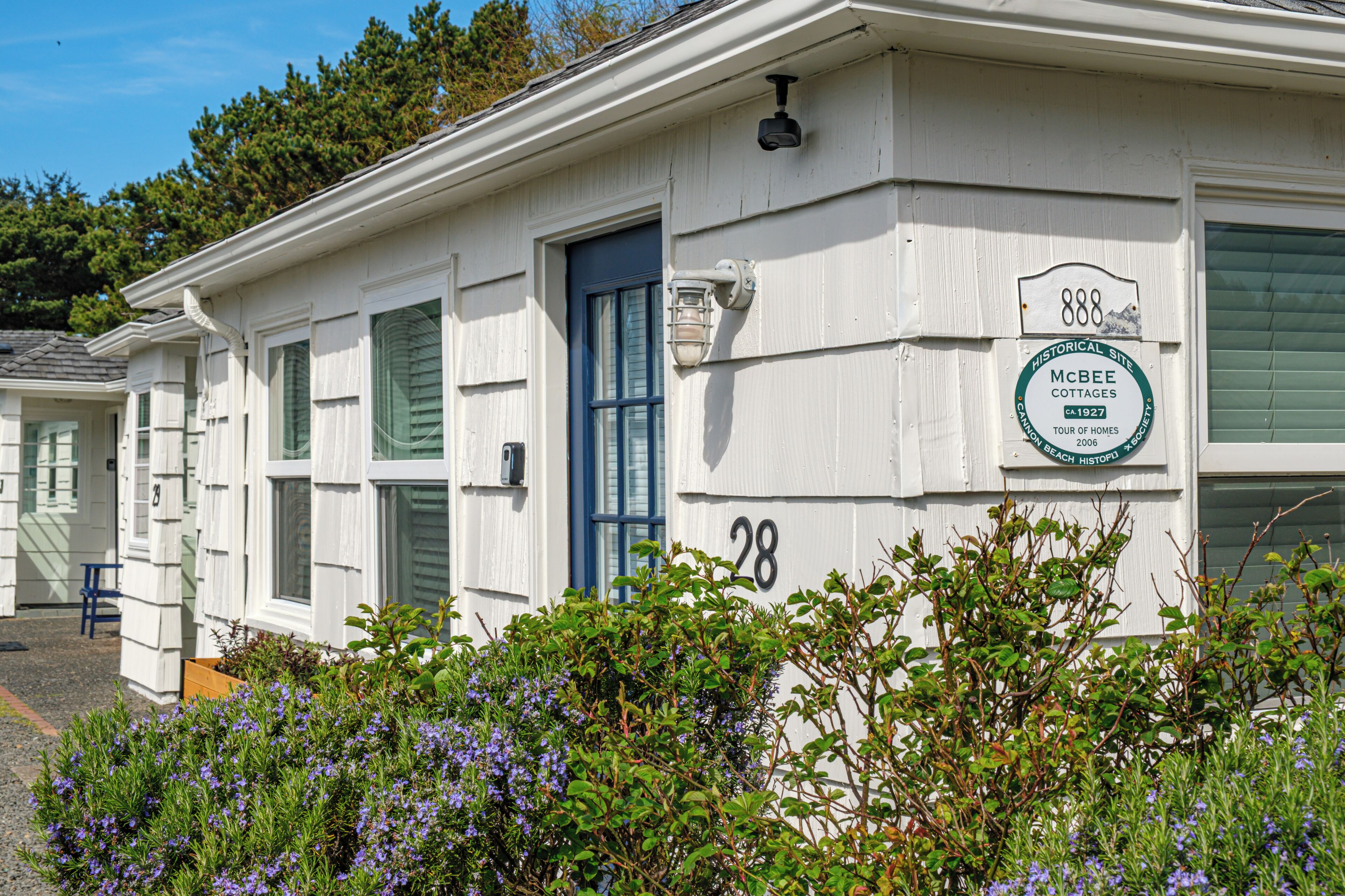 A white cottage with a blue door, labeled as number 28, part of the McBee Cottages.