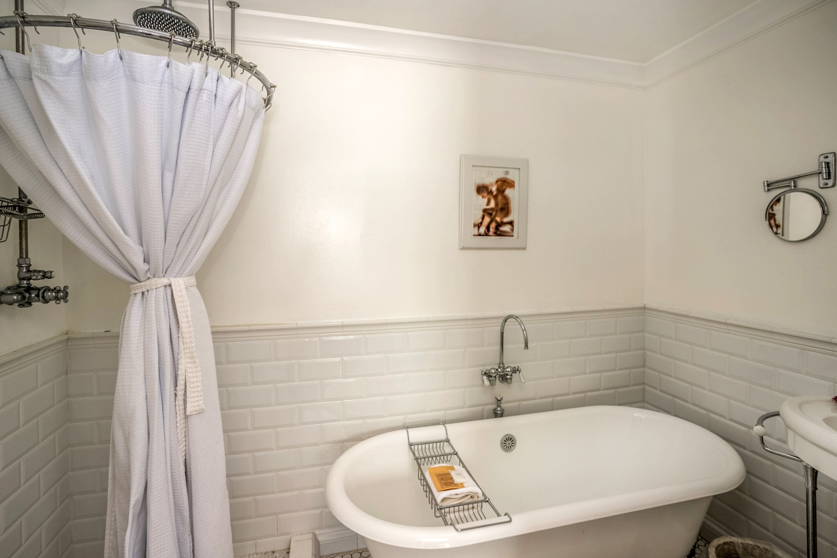 Bagno con vasca da bagno bianca, tenda da doccia, porta asciugamani, quadro incorniciato e porta carta igienica.