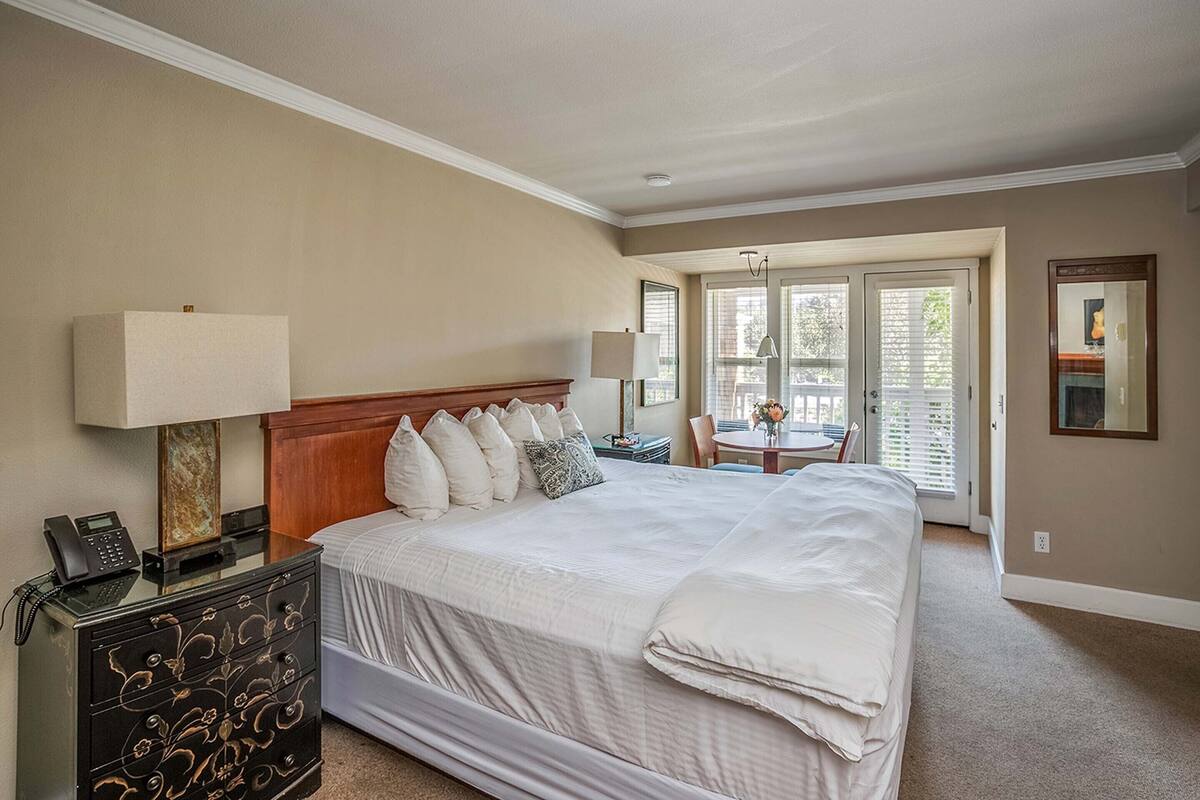 A hotel room with a large bed, bedside tables, a desk, and a view of the outdoors.