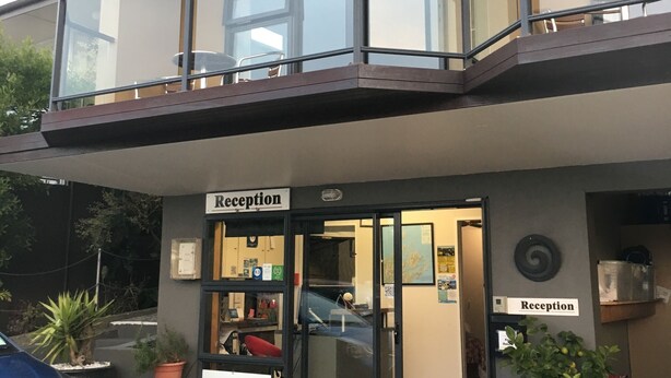 A reception area with a glass door, a red mat, and a sign. - Harbour View Motel (Picton)