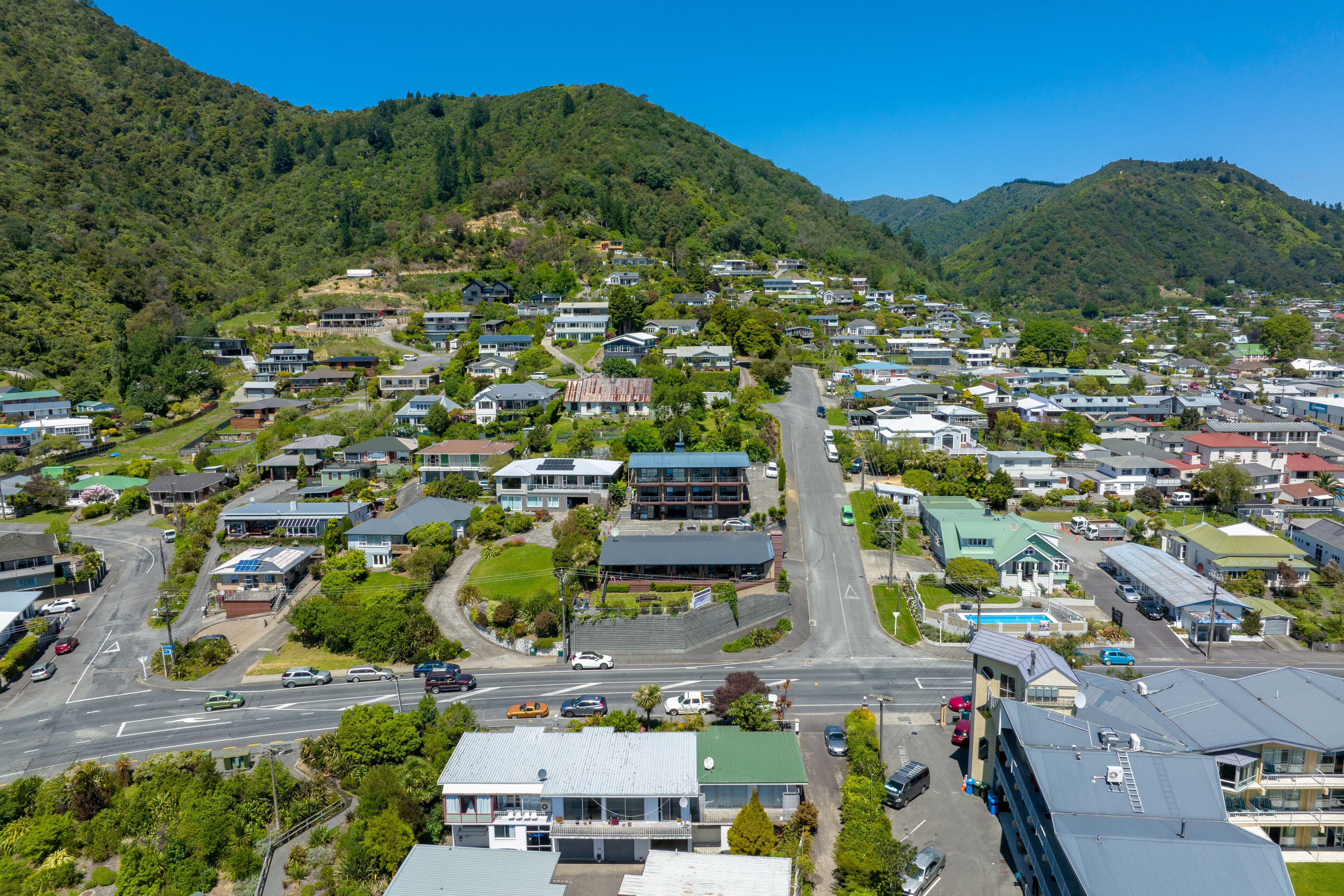 A residential area with houses, a main road, and a mountain backdrop.