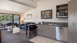 A modern kitchen with stainless steel appliances, a dining area with a table and chairs, and a large window offering a view of the outdoors. - Harbour View Motel (Picton)