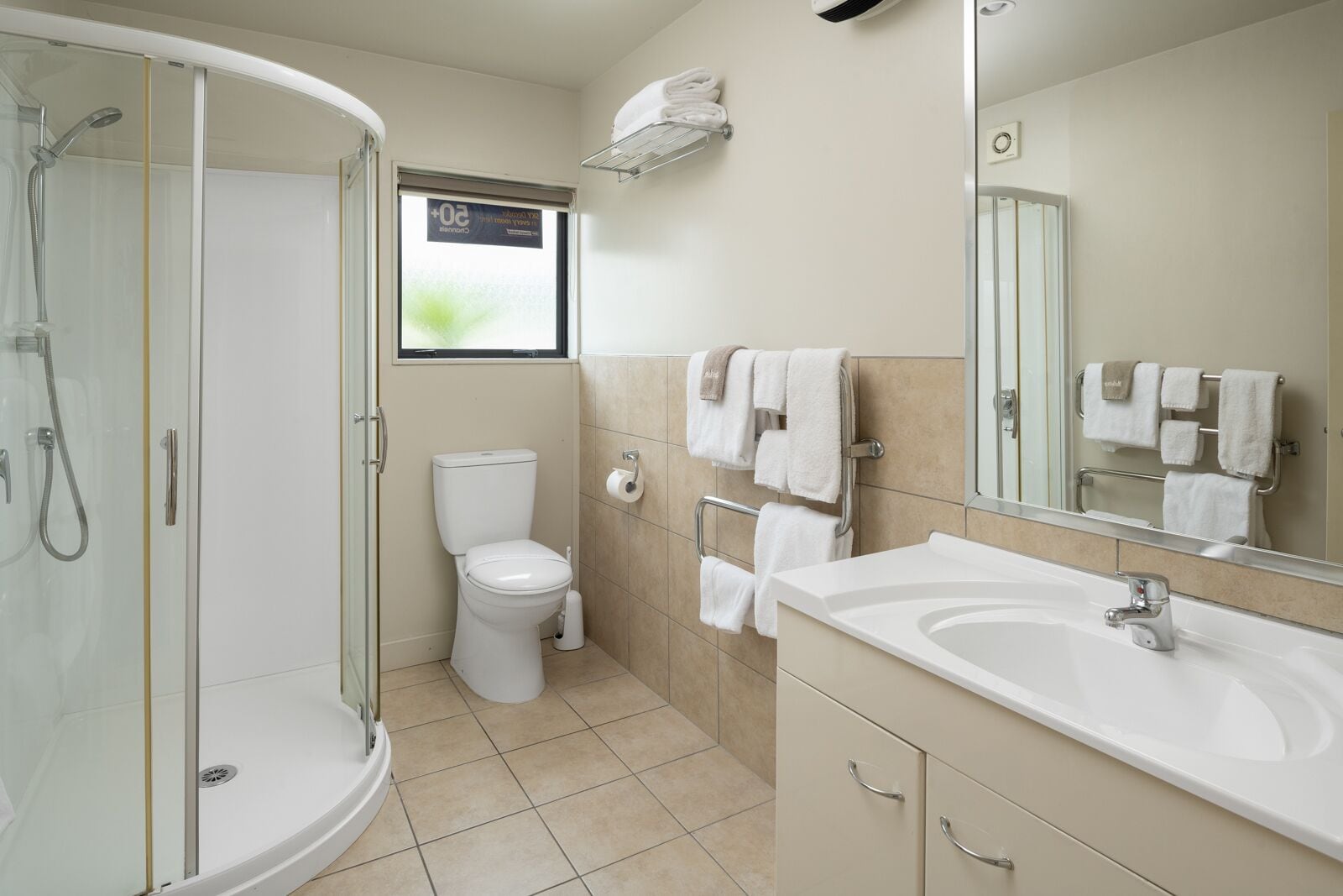 A modern bathroom with a glass-enclosed shower, a toilet, a sink, and a mirror.
