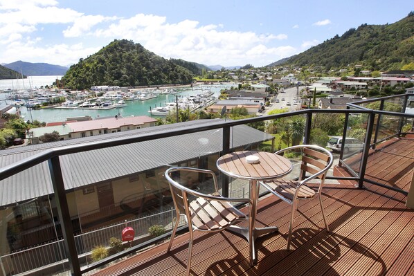 A balcony with a table and chairs overlooking a marina and a town. - Harbour View Motel (Picton)
