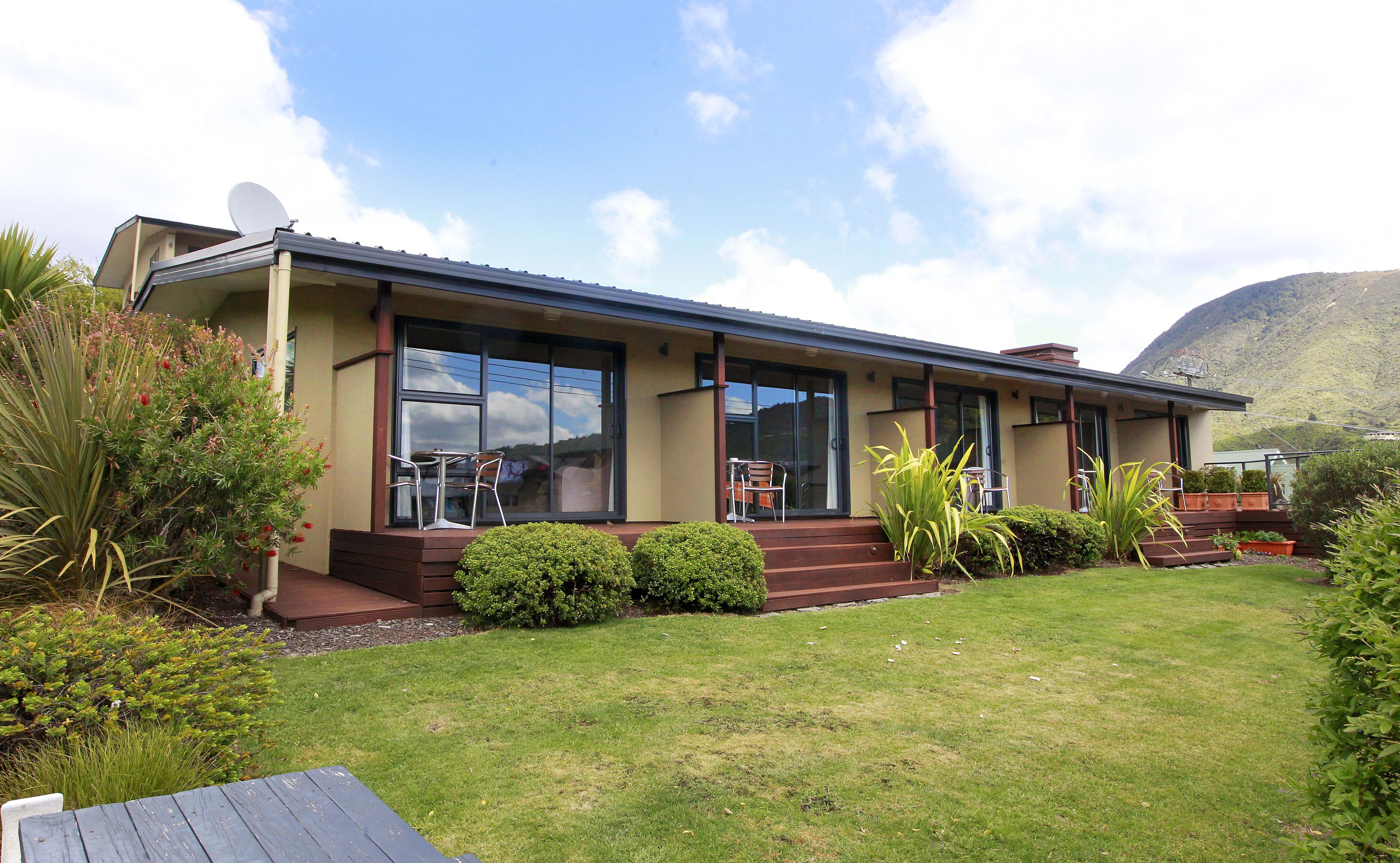 A two-story house with a large glass window, a satellite dish, and a well-maintained lawn.