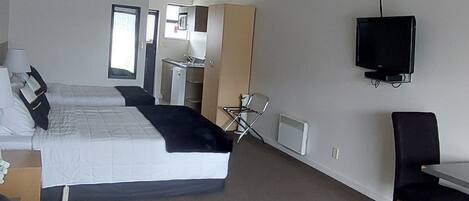 Habitación de hotel con cama, televisor, sillón y sofá.
