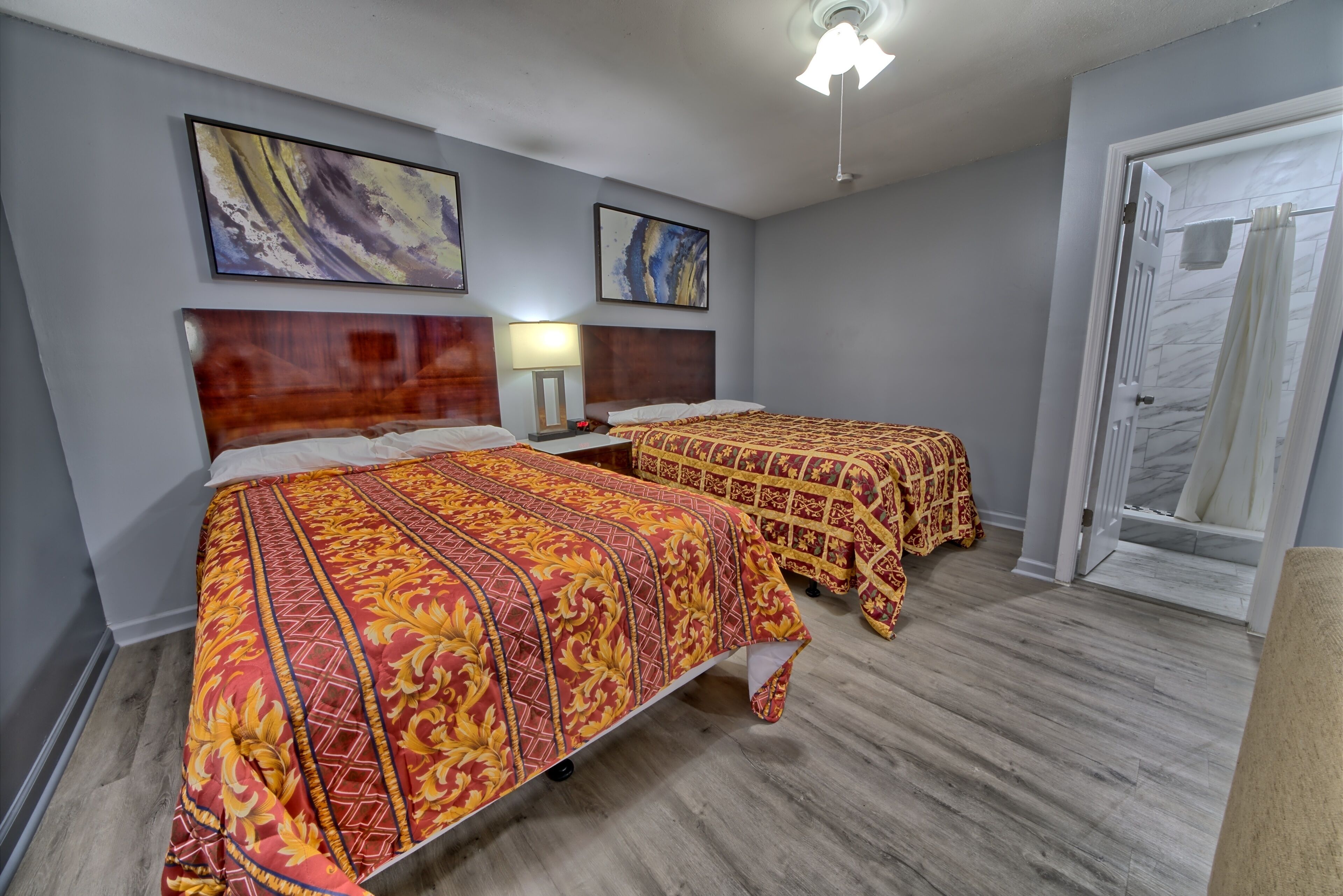 Une chambre d’hôtel avec deux lits, des têtes de lit en bois et des œuvres d’art accrochées aux murs.