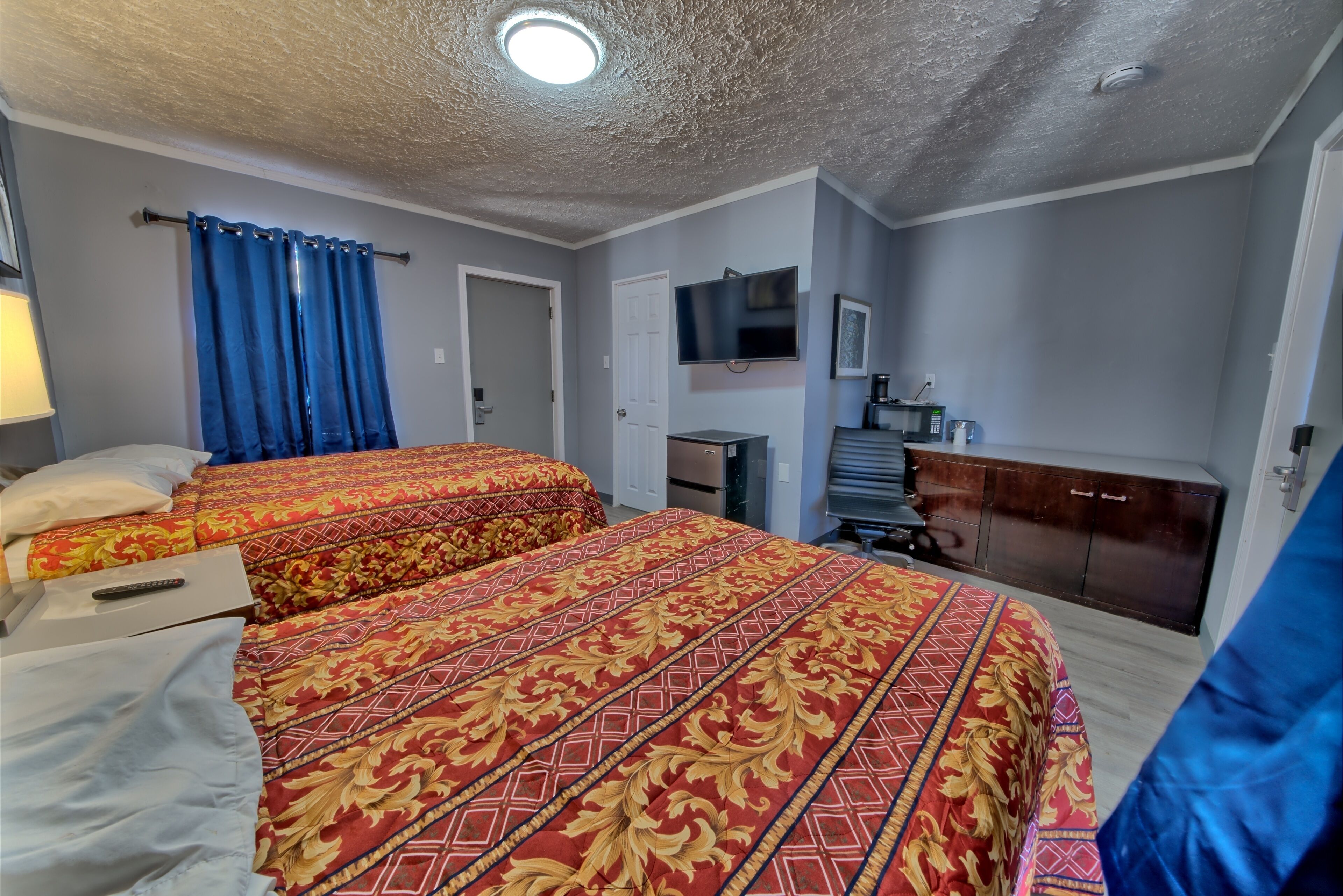 Habitación de hotel con dos camas, televisión, escritorio y armario.