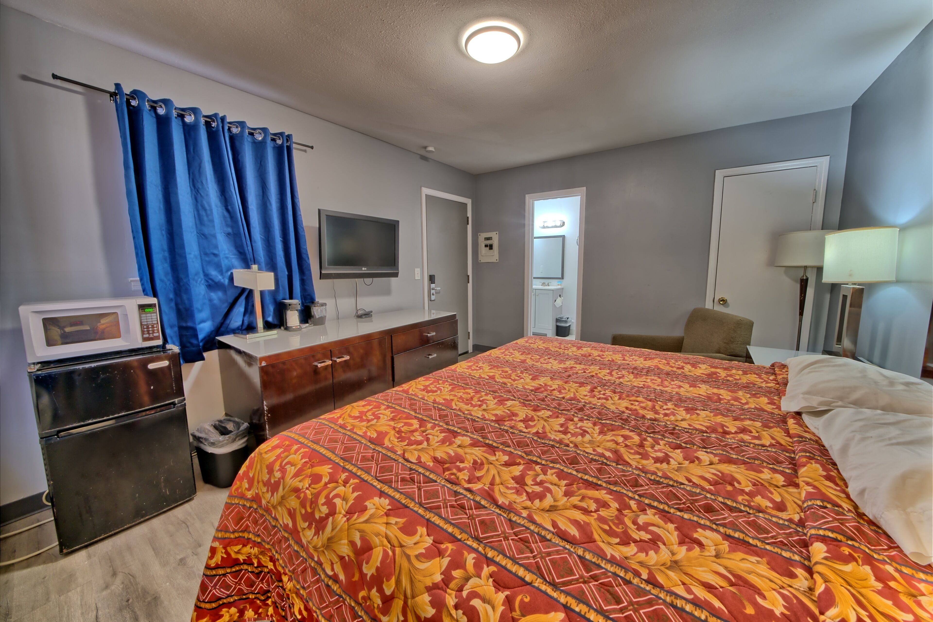 A hotel room with a large bed, a TV, a microwave, and a small refrigerator.