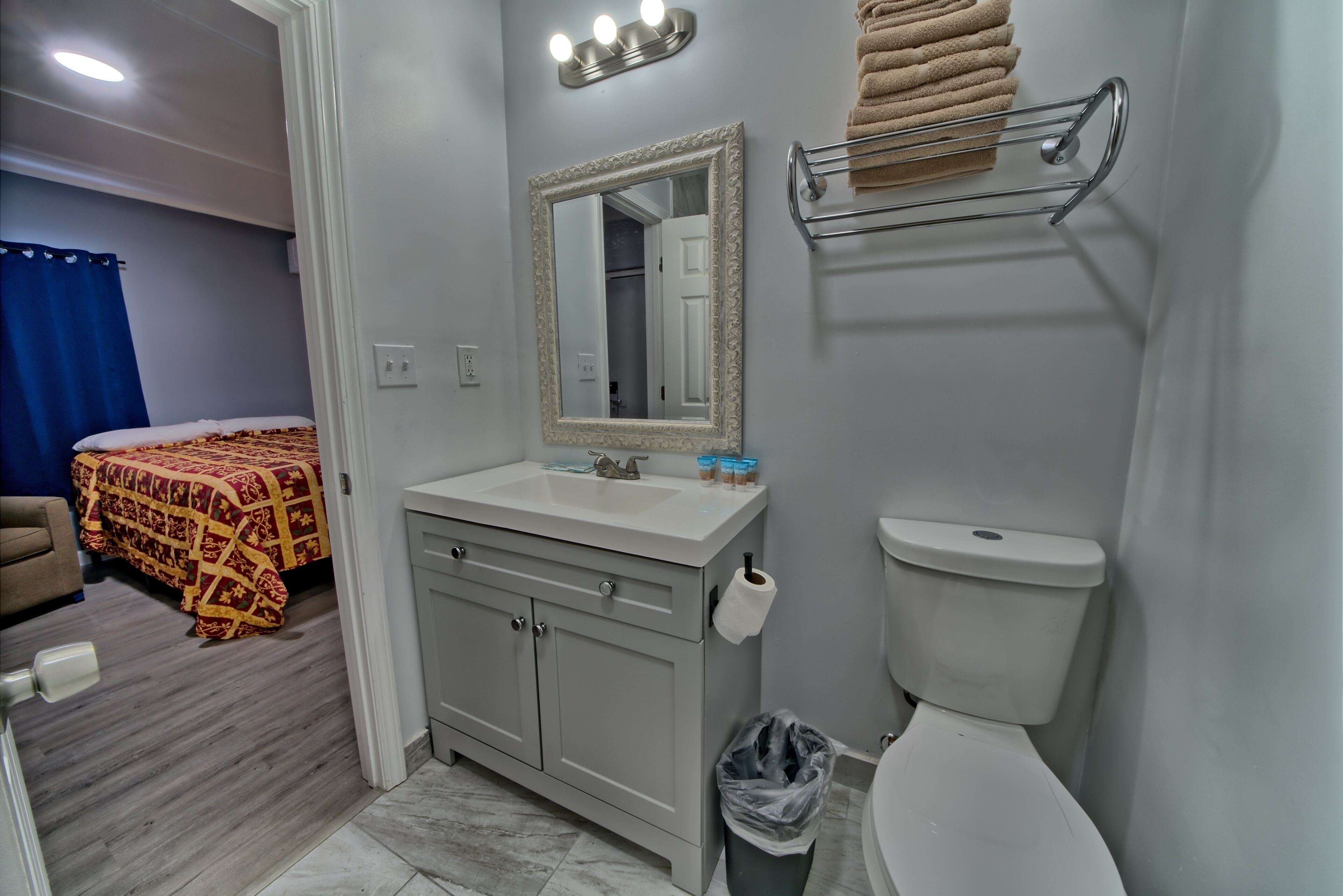 A bathroom with a toilet, sink, mirror, and towel rack.
