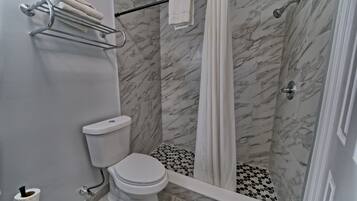 A bathroom with a toilet, shower, and a towel rack.